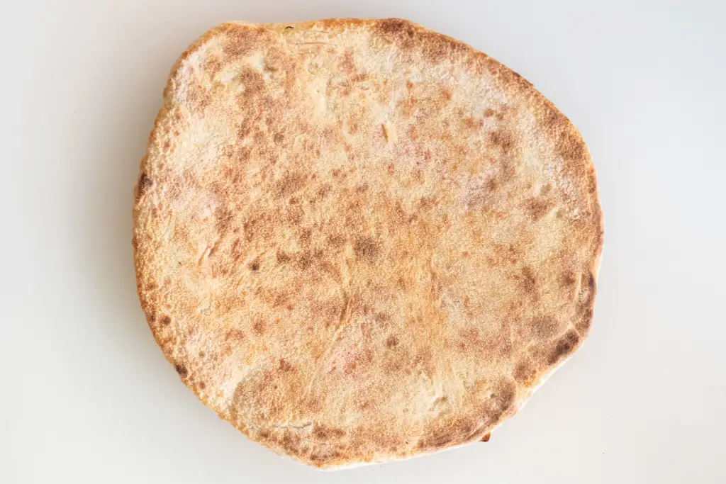 Pizza base baked on a Steel Craft baking steel, deeply charred and browned