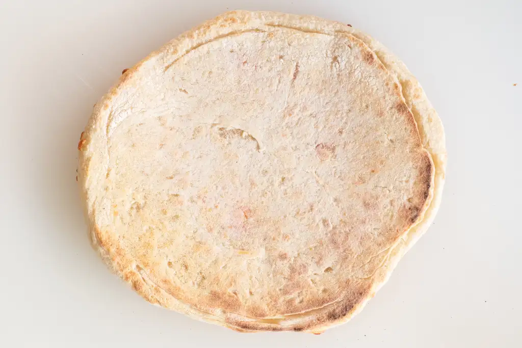 Pizza base baked on a regular pan, pale with little colour