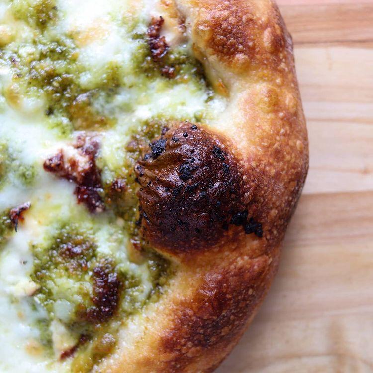 Overhead shot of a pesto pizza baked on a Steel Craft steel