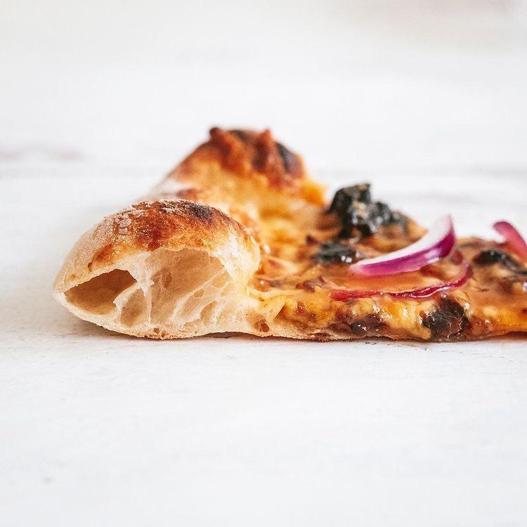 Close-up of a pizza slice showing an airy, charred crust